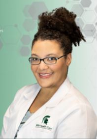 Dr. Chioma Torres. A woman wearing a white lab coat, smiling, and leaning against a wall. with a green background.