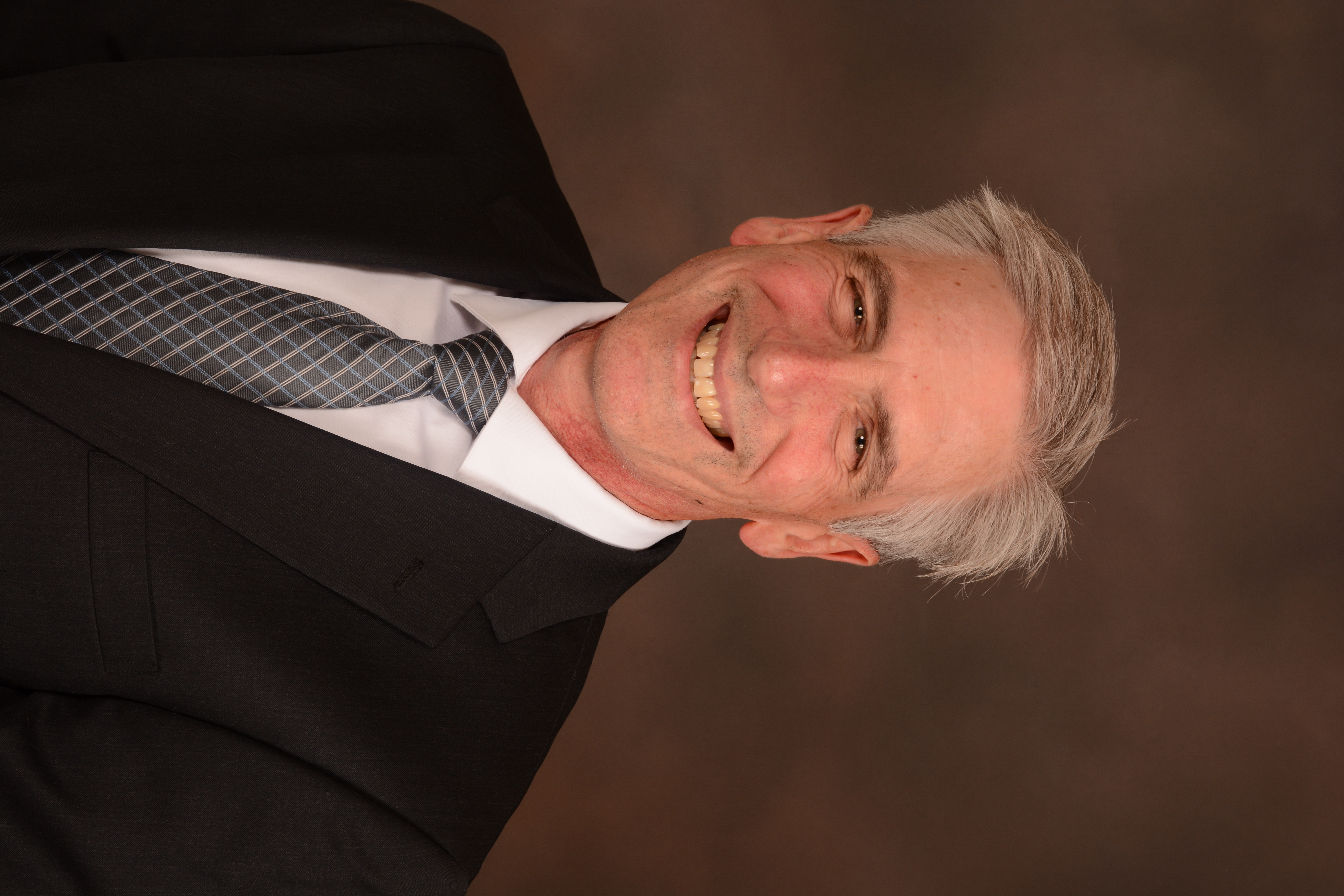 Dr Steve Erickson is wearing a suit, smiling, and has short white hair.