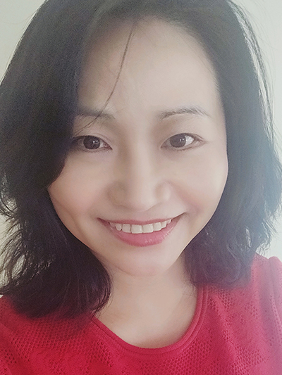 Photo of Ke Zhang. Ke is smiling, has shoulder-length black hair, and is wearing a red shirt.