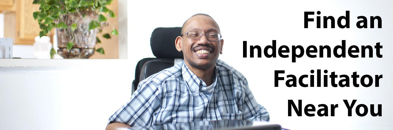 Man wearing plaid shirt sitting at table and smiling - Click on this button to Find an Independent Facilitator Near You